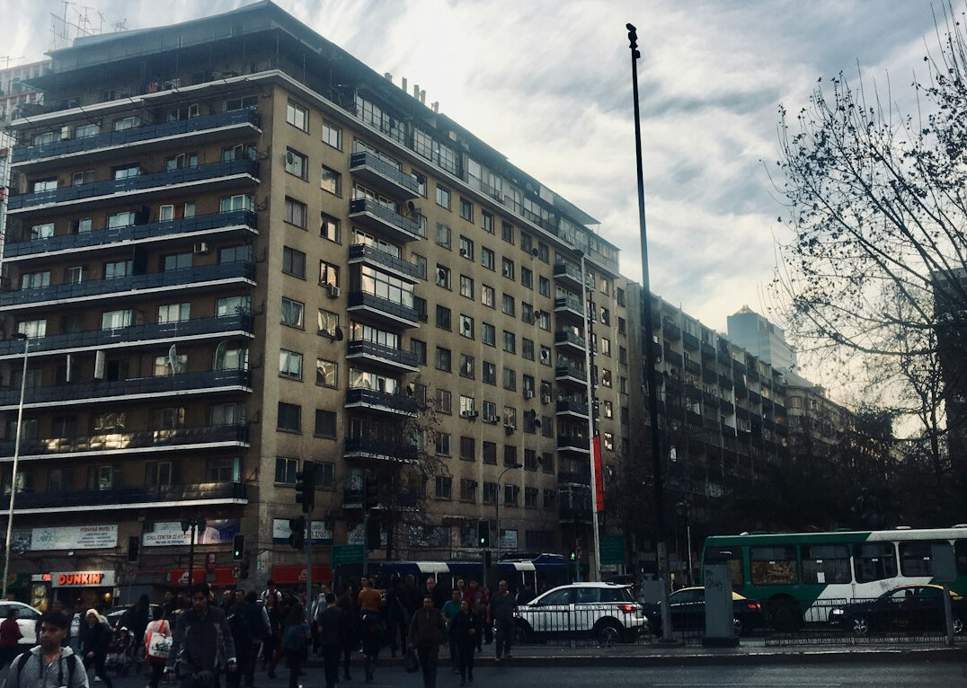 People waiting to cross a busy street in a Chilean city