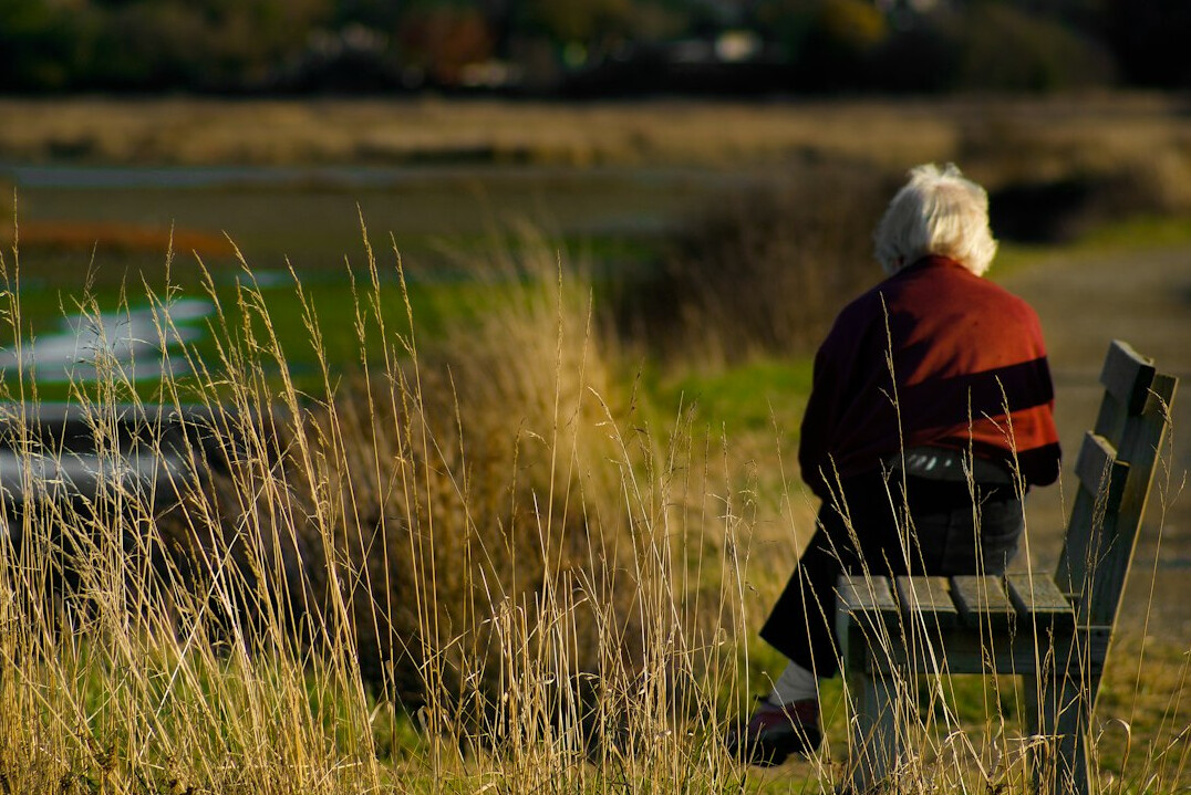 elderly person waiting on bench